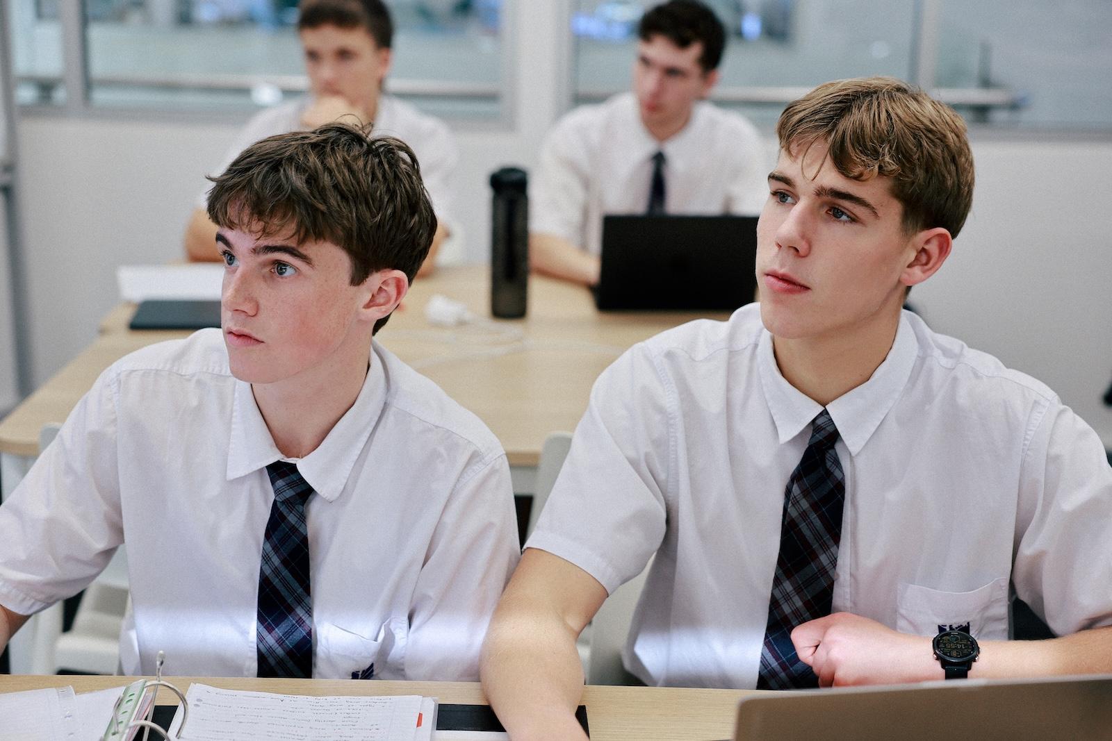 Male secondary students attentively following a lesson in a bright classroom.