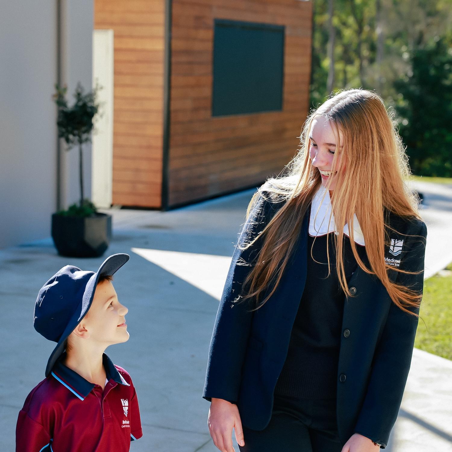 Female senior school captain smiling at primary school boy exemplifying caring cross-age mentoring