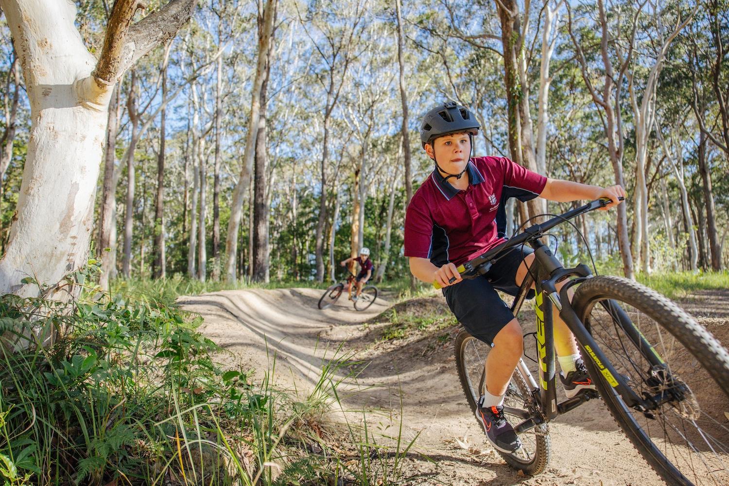 Student navigating a mountain biking track surrounded by Australian bushland