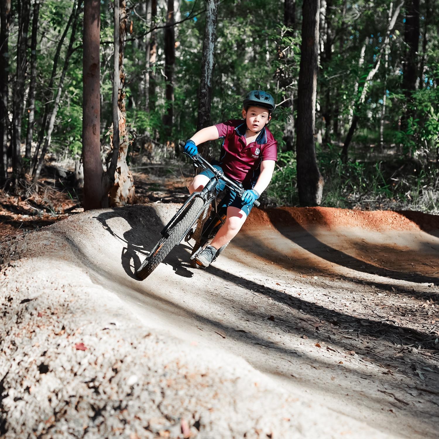 A school student enjoying mountain biking on a Medowie forest trail as part of the outdoor co-curricular activities.