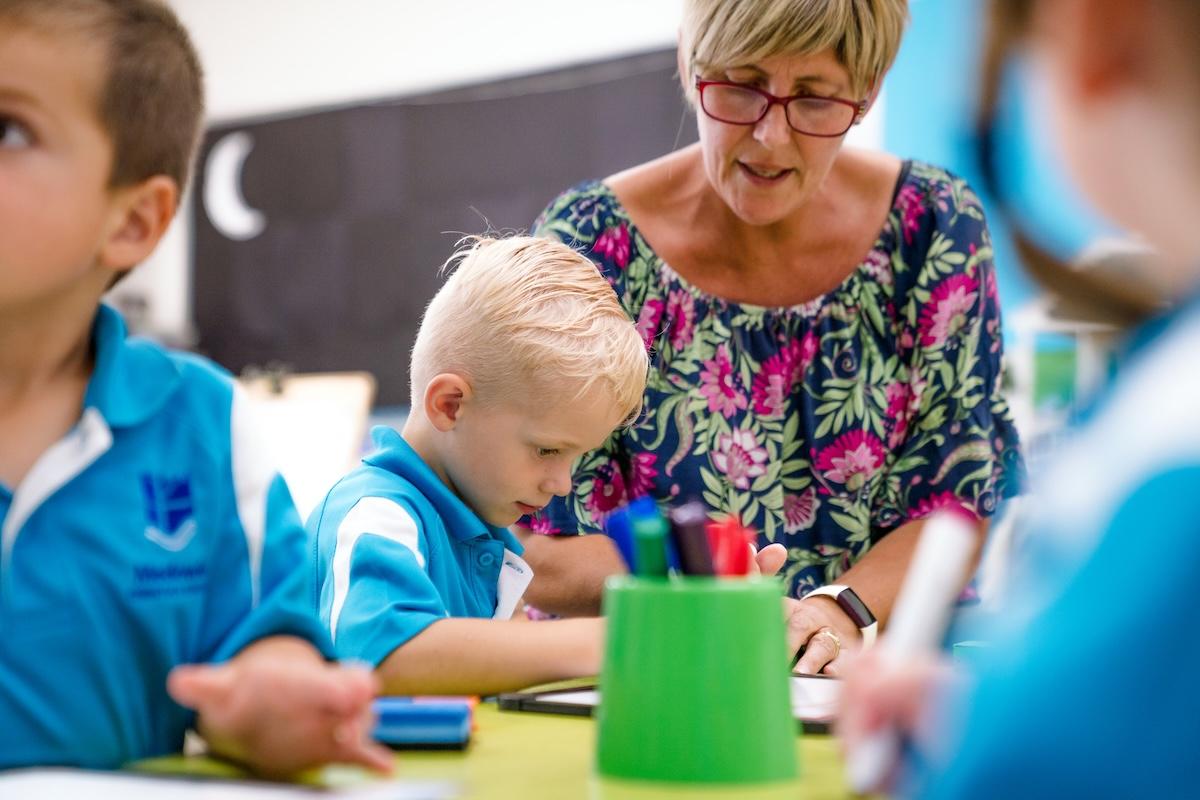 Prep student focused on a classroom activity with teacher guidance at Medowie School.