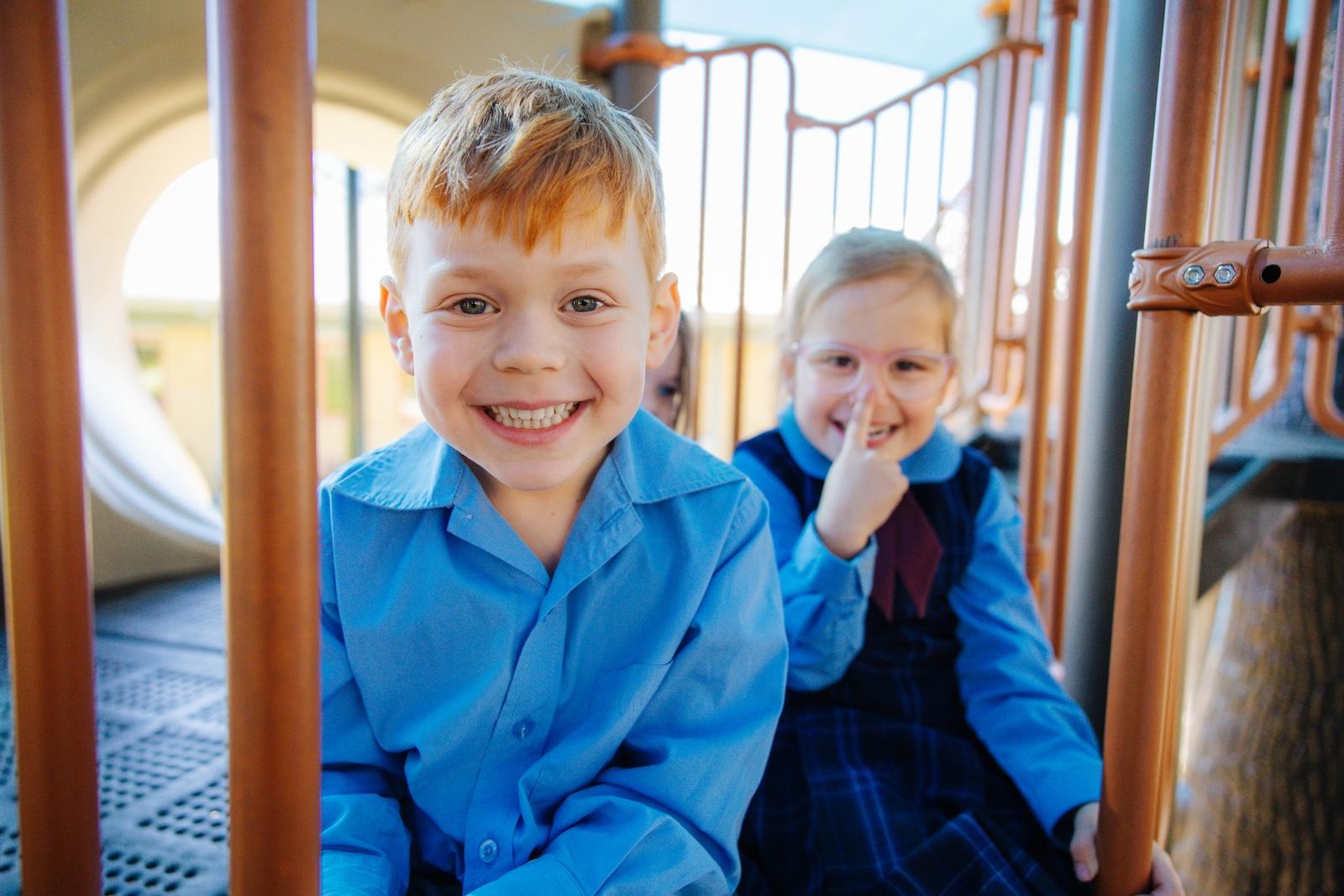 Primary school students smiling while playing on the school playground at a Christian school in Port Stephens NSW.