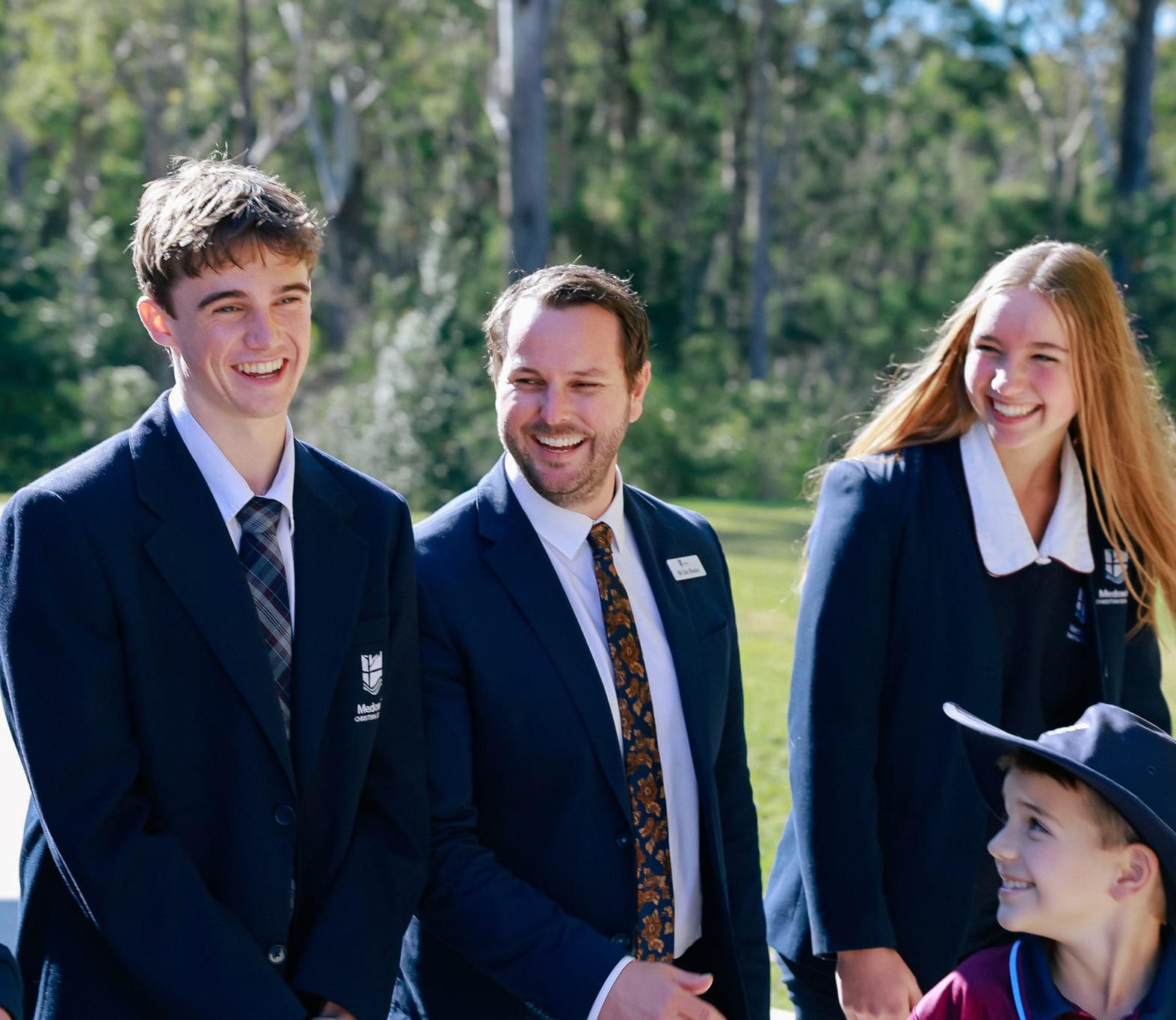 Principal of Medowie Christian School walking with high school and primary students on the school grounds.