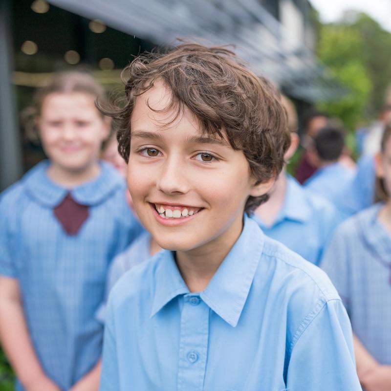 Close-up of a student smiling during a school tour, emphasizing the friendly atmosphere at the school.