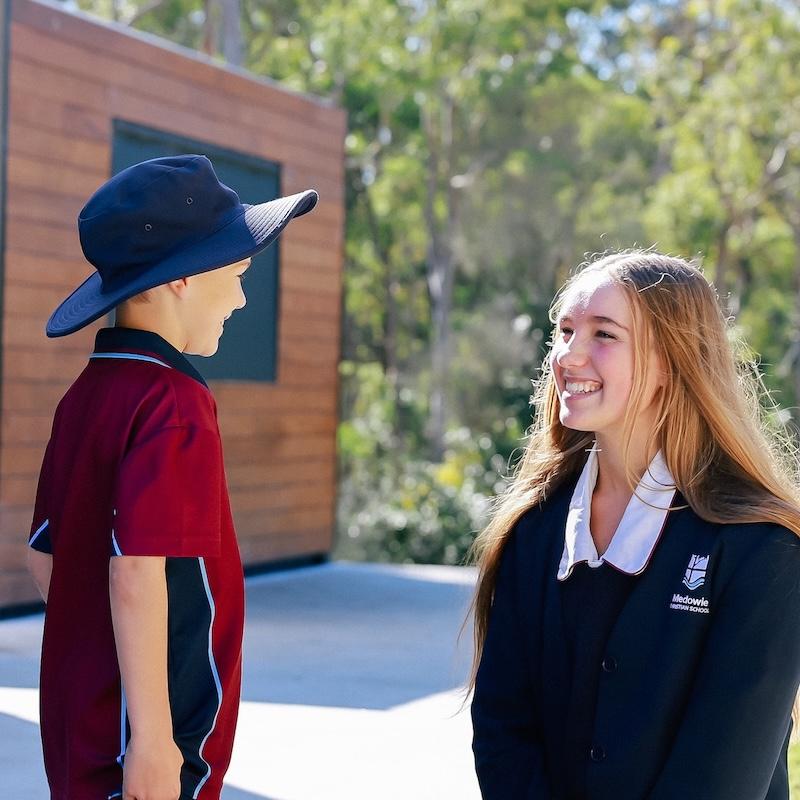 Senior student smiling and engaging with a younger student, emphasising the love and support of the school community.