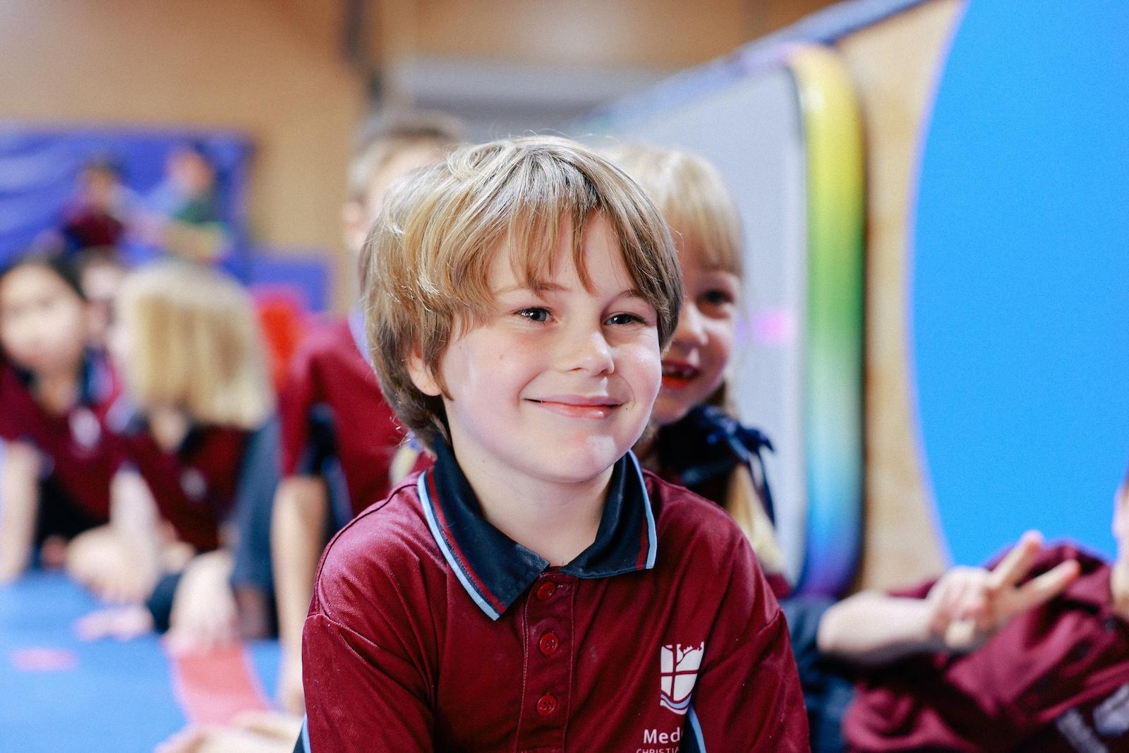 Teacher engaging with a young boy in a classroom setting, showcasing personalised care and support for holistic growth.