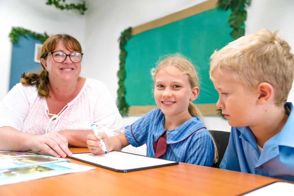 Teacher supporting two students with learning activities, highlighting personalised care and academic support at Medowie Christian School.