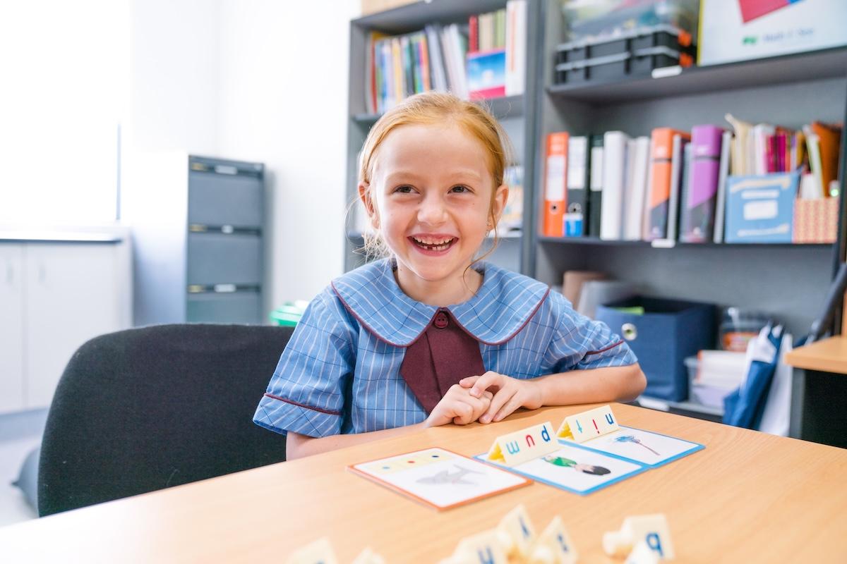 Young girl smiling in the classroom during a learning activity, embodying the nurturing environment of Medowie Christian School.